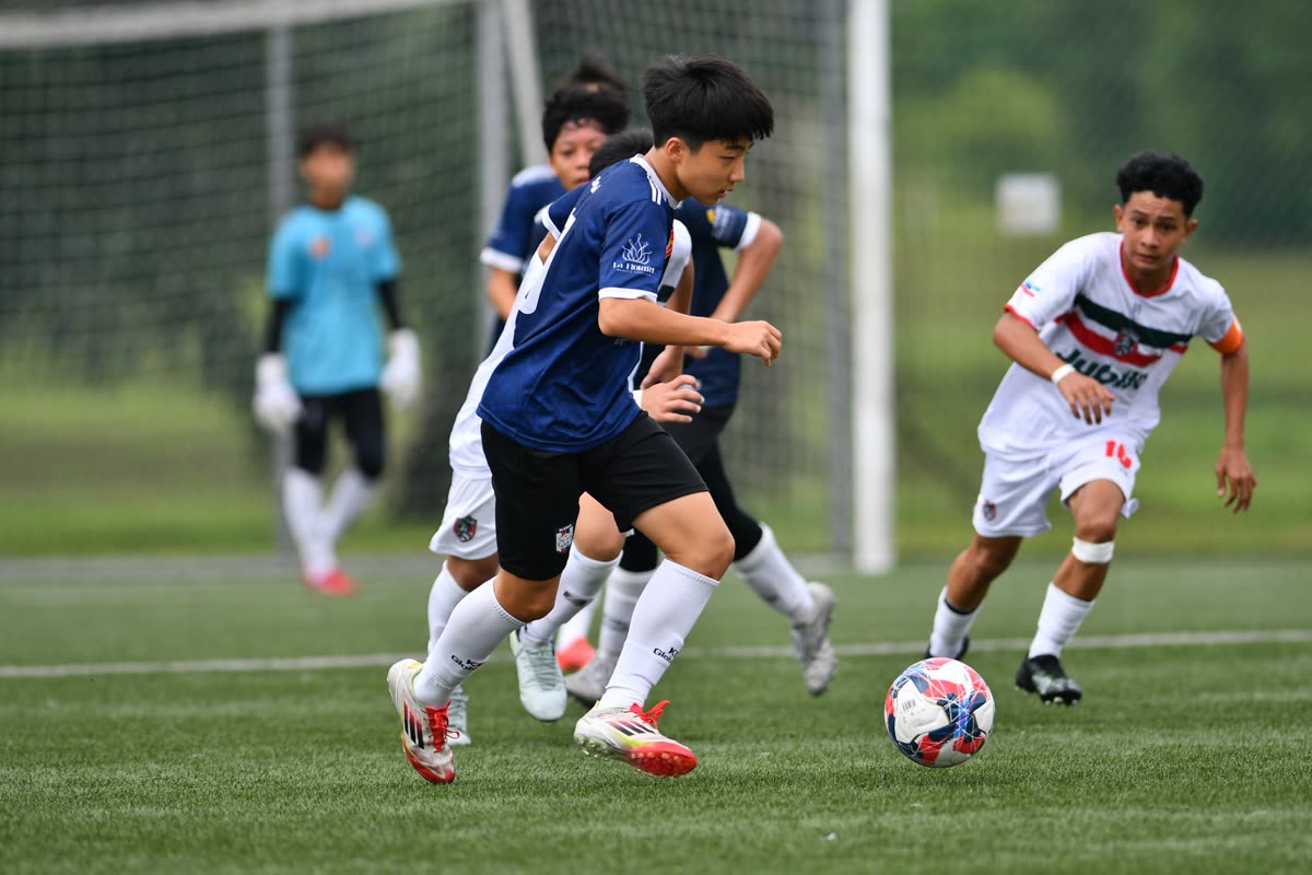 A player drives forward with the ball during a KFAM International Youth Cup match